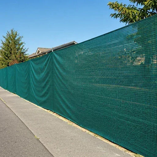 Green 4' x 50' 90% privacy fence mesh tarp installed along a perimeter barrier