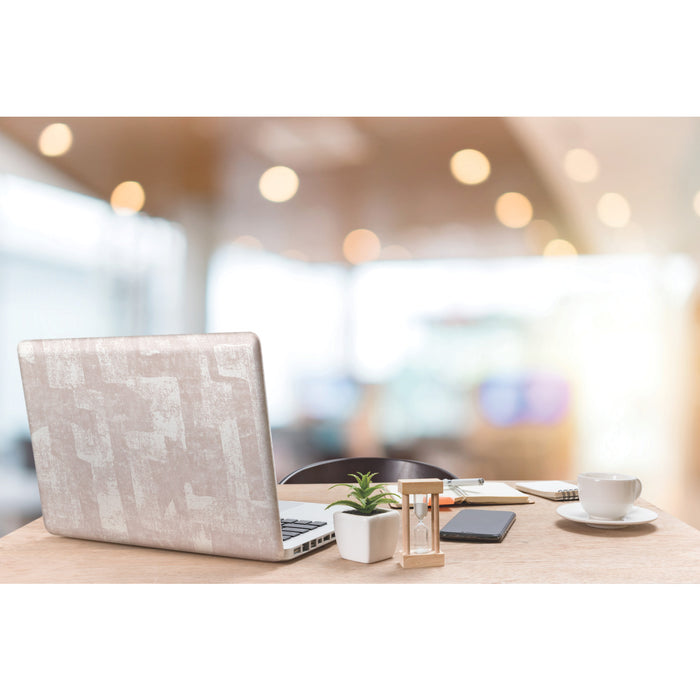 A modern workspace with a laptop, potted plants, an hourglass, a phone, a notebook with a pen, and a cup and saucer on a wooden table. The background features softly blurred blush tones and Nikki Chu Capetown Peel and Stick Wallpaper from WallPops with geometric design, enhanced by warm lights that create a cozy, inviting atmosphere.