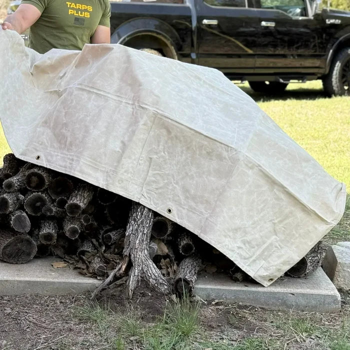 White 10' x 12' canvas tarp protecting stacked firewood from outdoor weather exposure